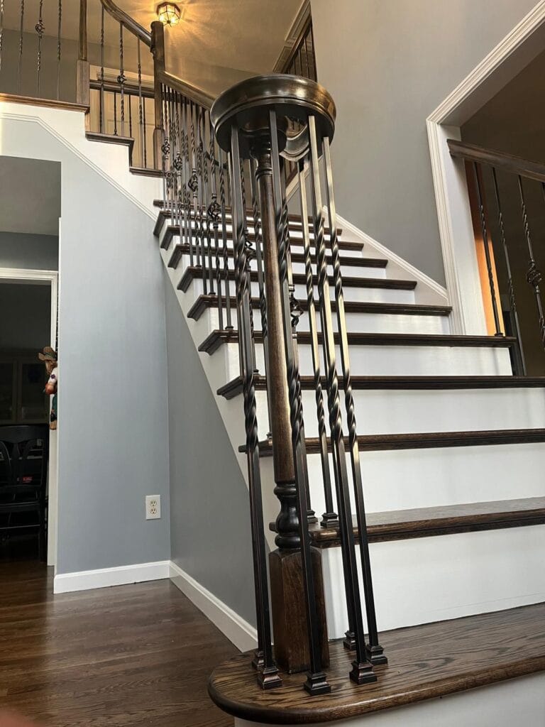 Staircase featuring dark walnut-stained hardwood steps and ornate metal railing, showcasing GB Hardwood Flooring's craftsmanship in home transformations.
